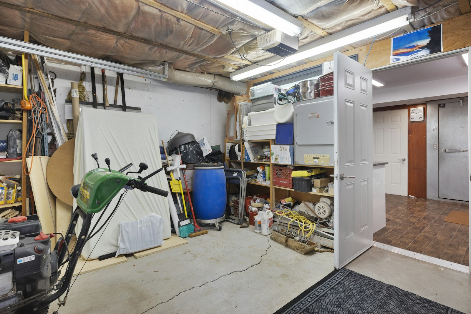 Garage packed with stored household items, tools and boxes on shelving