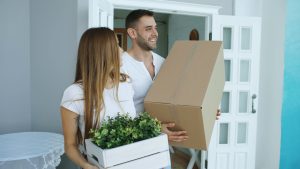 Couple in conversation surrounded by moving boxes while sharing out the work of a move