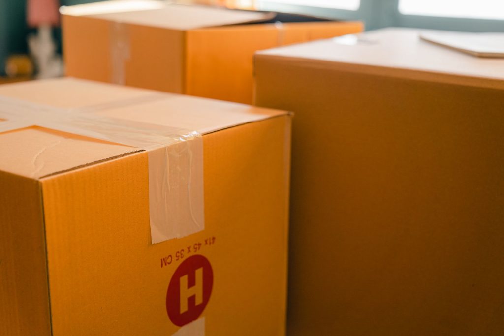 Sealed cardboard removal boxes stacked beside a window in a sunlit empty room