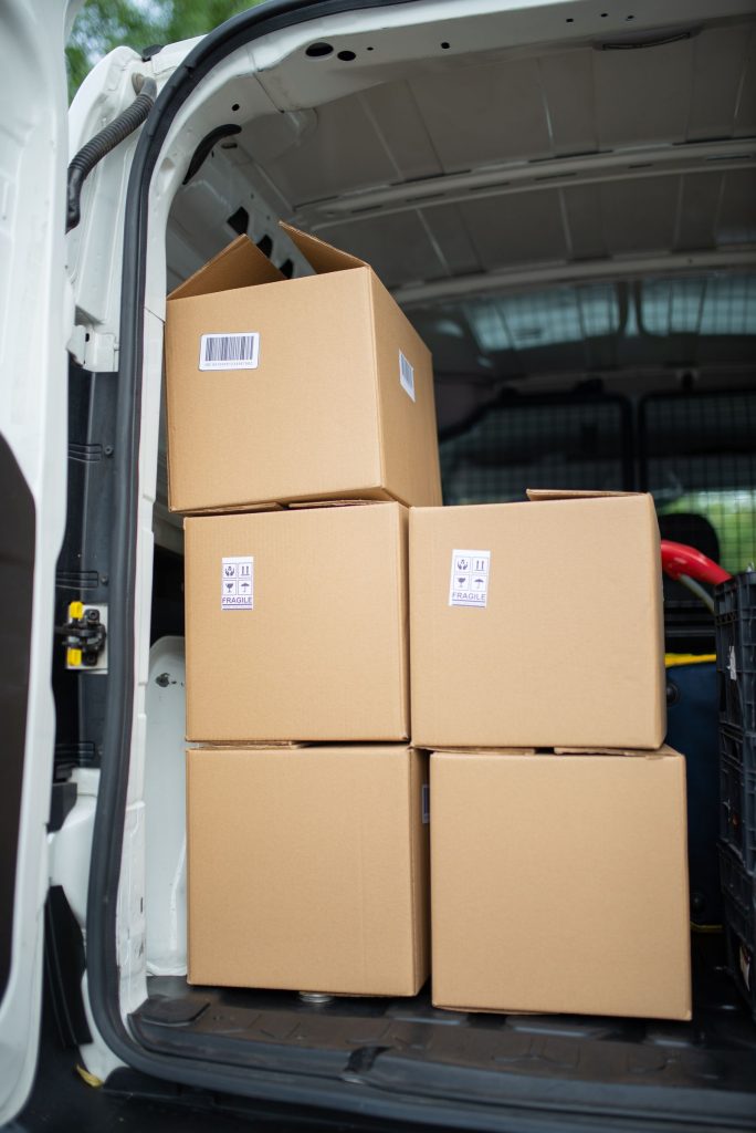 Cardboard boxes stacked inside the open rear load area of a box van